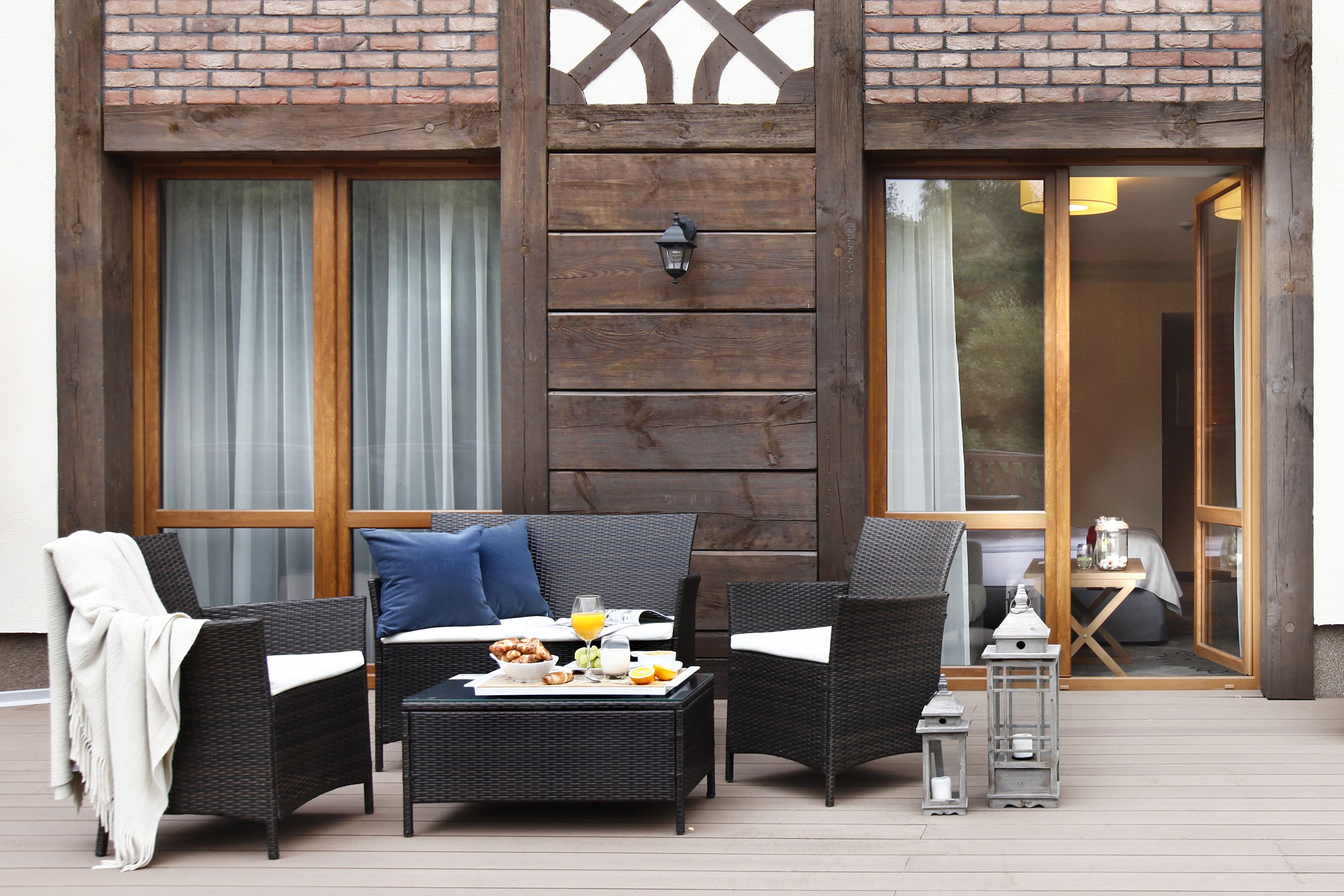 An outdoor seating area with wicker furniture, a table with breakfast items, and a lantern.