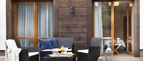 An outdoor seating area with wicker furniture, a table with breakfast items, and a lantern.