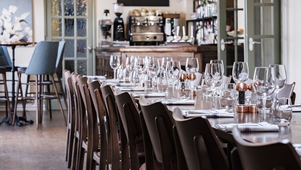Ein Essbereich mit einem langen Tisch, gedeckt für eine Mahlzeit, Stühlen und einer Bar im Hintergrund.