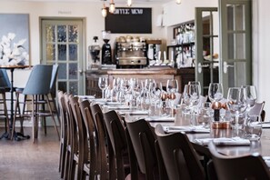 A dining area with a long table set for a meal, chairs, and a bar area in the background. - The Bower Inn (Bridgwater)