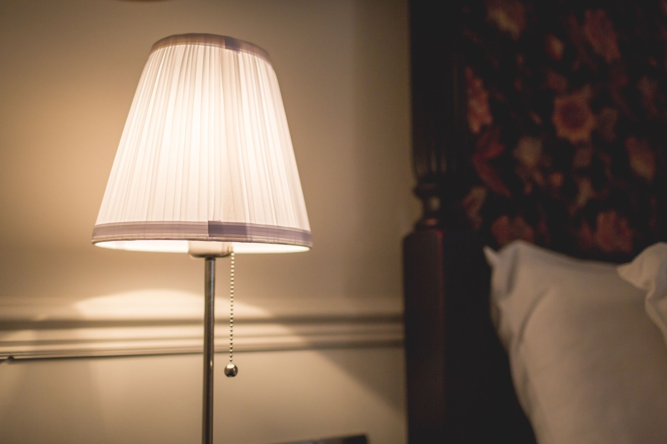 A lamp with a pleated shade on a bedside table.