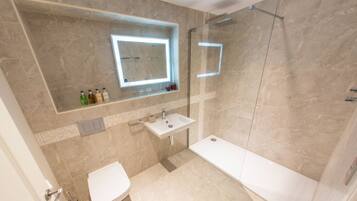 A modern bathroom with a bathtub, toilet, sink, and a glass-enclosed shower.