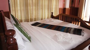 A neatly made bed with white linens, a striped blanket, and two white towels.