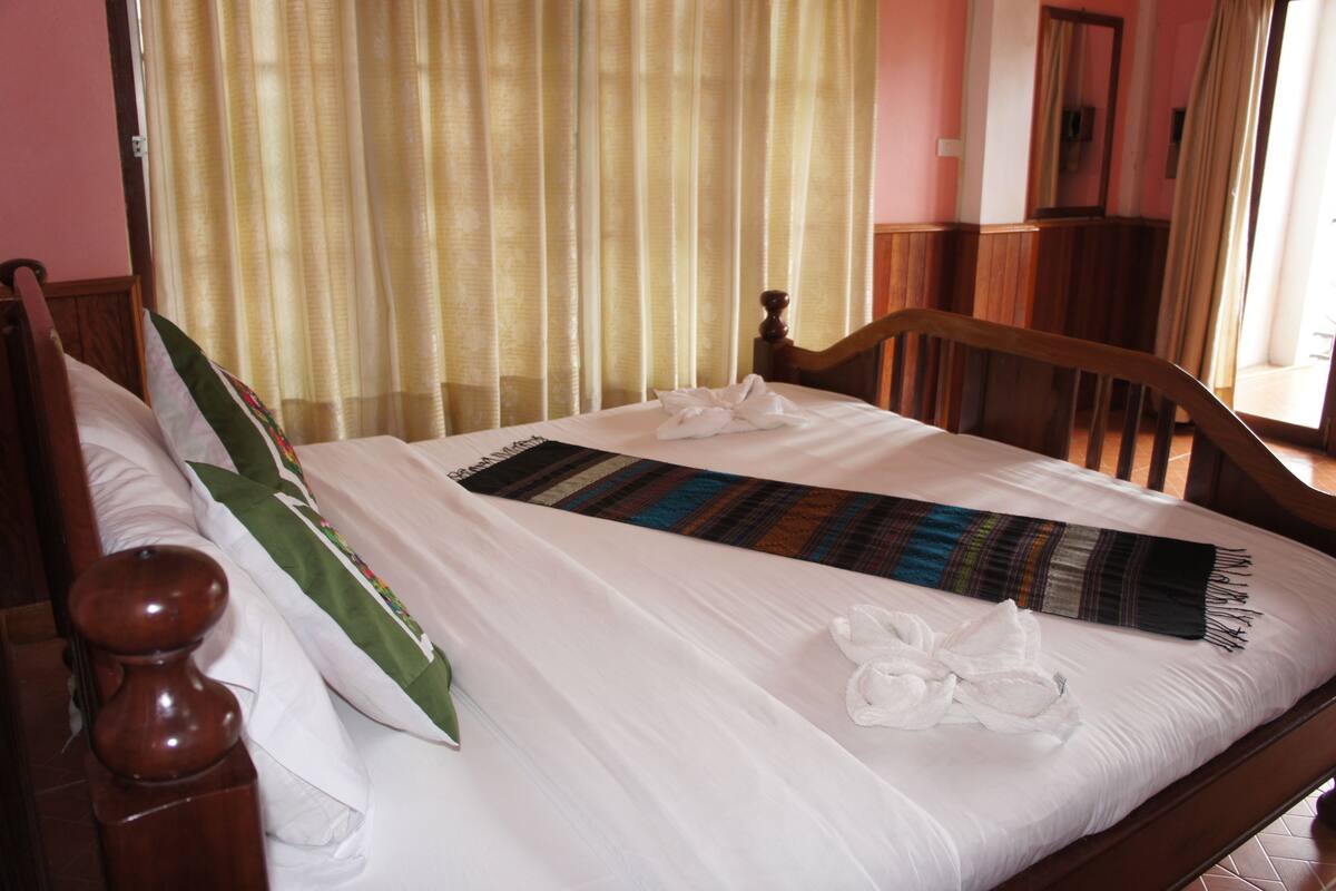 Un lit bien fait, avec des draps blancs, une couverture à rayures et deux serviettes blanches.