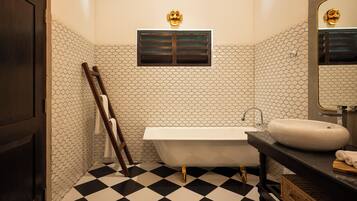 A bathroom with a black and white checkered floor, a white bathtub, a white sink, and a mirror with a gold frame.