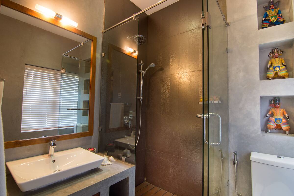 A modern bathroom with a glass-enclosed shower, a large mirror, and a sink.