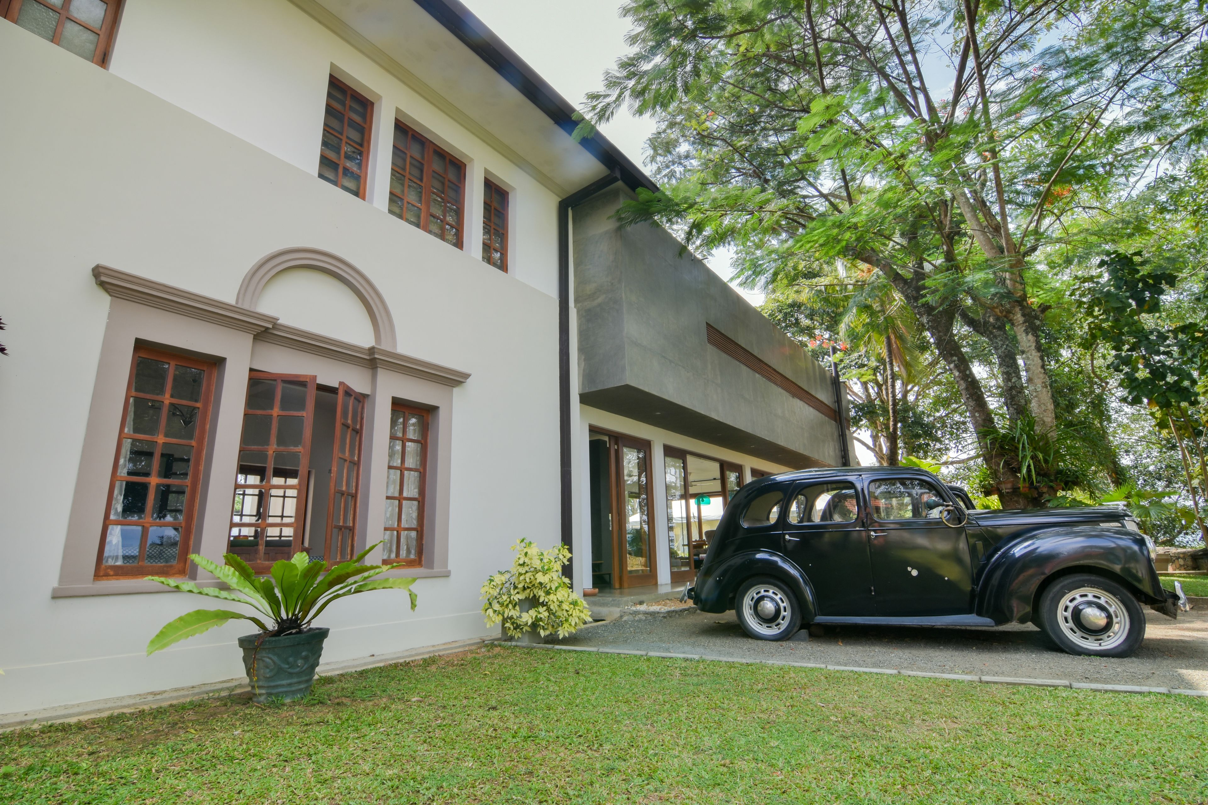 A vintage black car parked in front of a white building with large windows and a door.