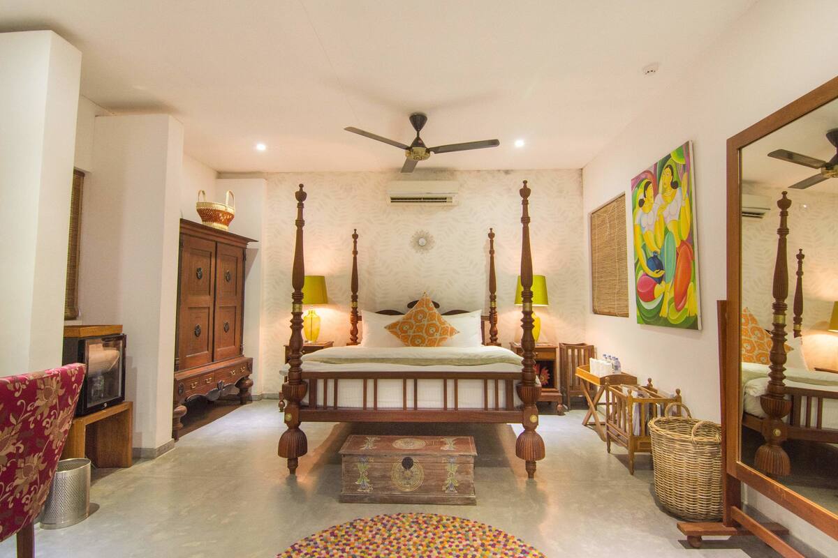 A traditional bedroom with a four-poster bed, a ceiling fan, and a large mirror.