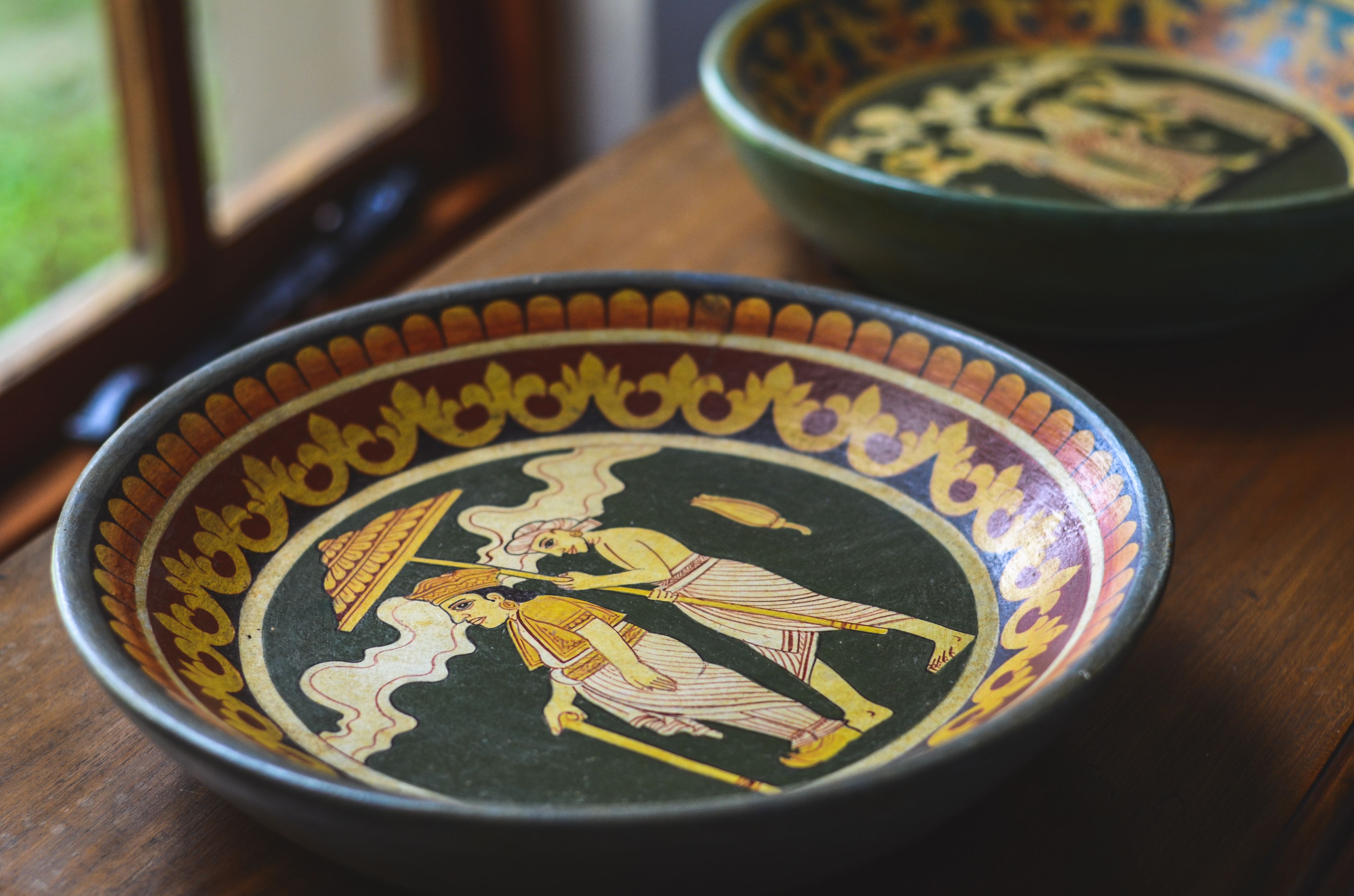 Un tazón de cerámica con motivos de arte griego antiguo sobre una mesa de madera.