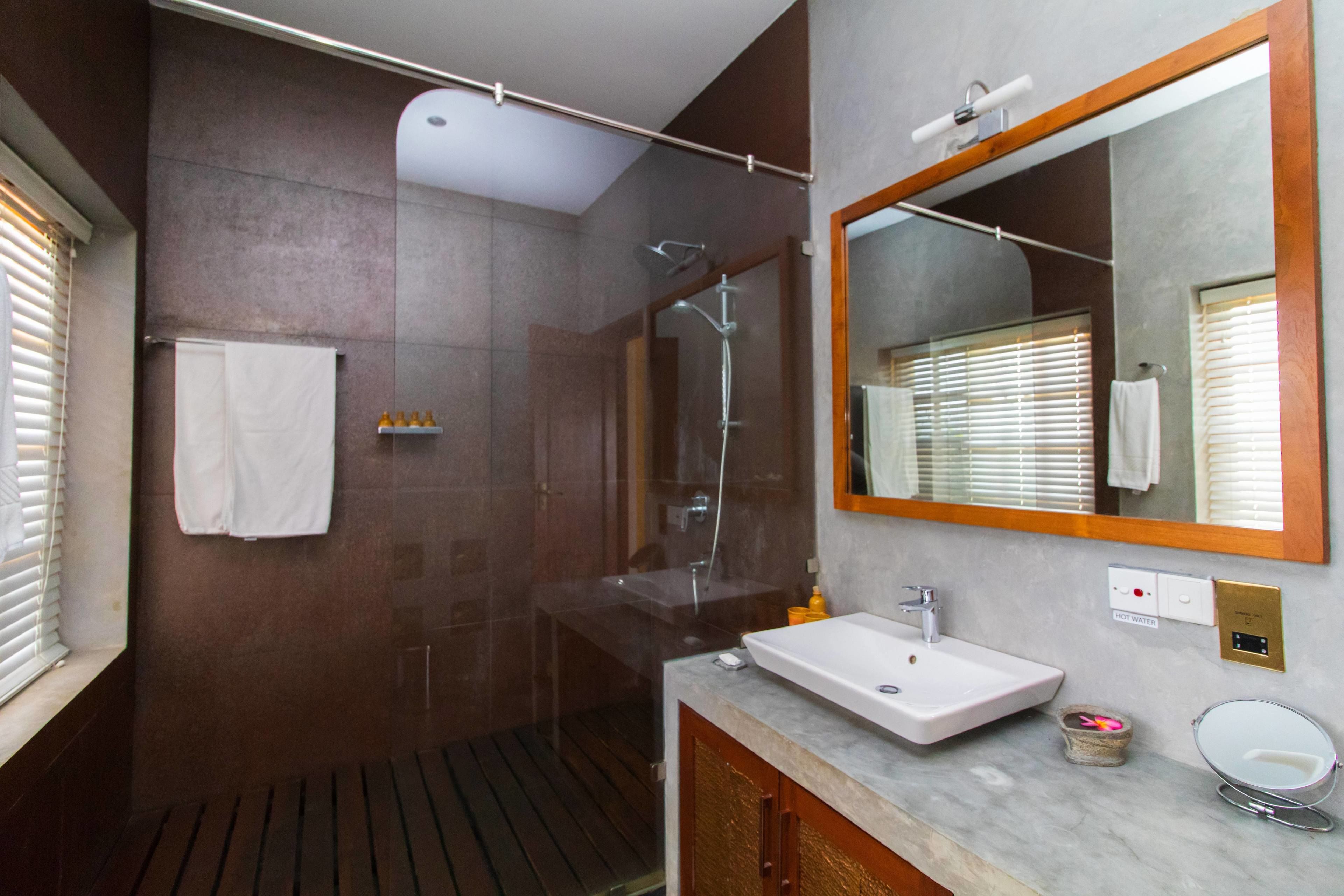 A modern bathroom with a glass-enclosed shower, a large mirror, and a sink with a vanity.