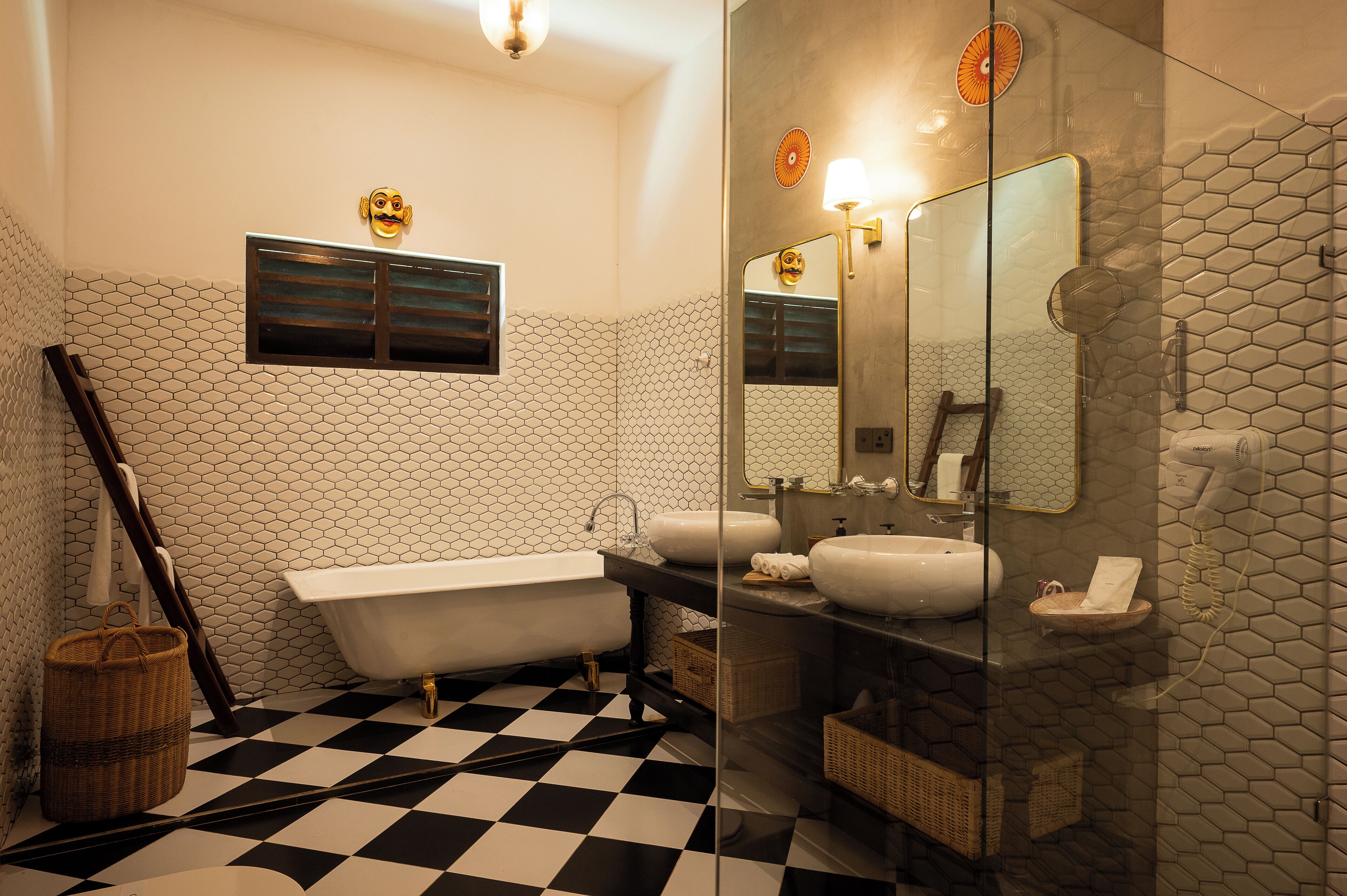 Un bagno con pavimento a scacchi, una vasca, uno specchio grande e una parete rivestita di piastrelle esagonali.