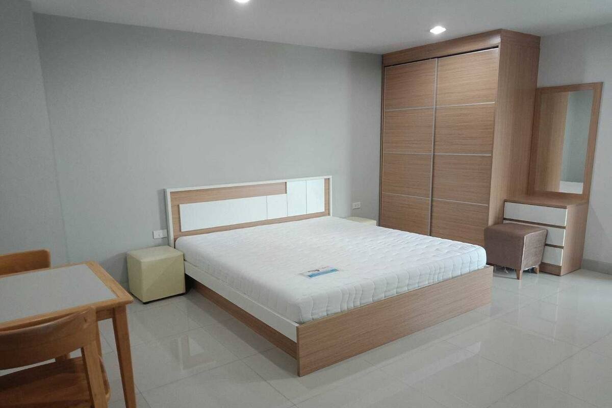 A modern bedroom with a wooden bed, a bedside table, a chair, and a wardrobe.