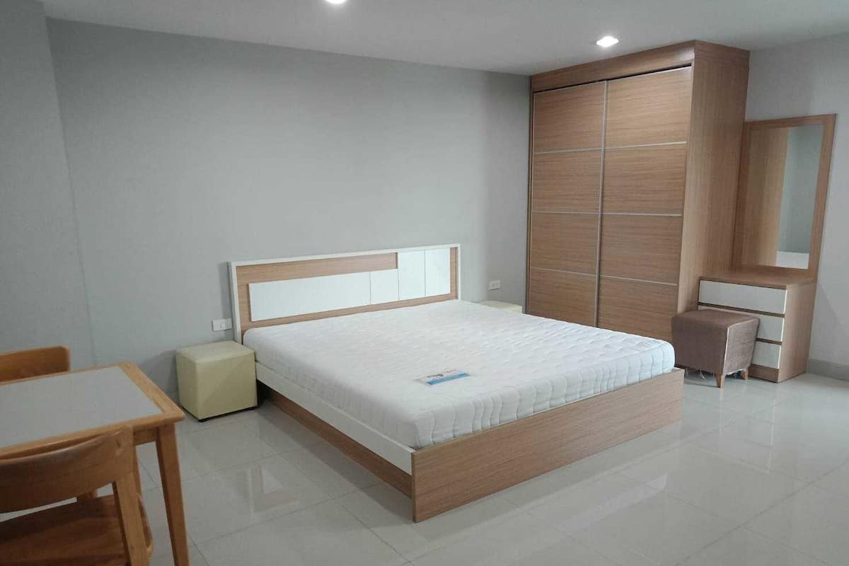 Une chambre à coucher moderne avec un lit en bois, une table de chevet, une chaise et une armoire.