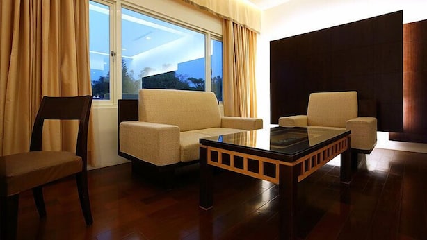 A modern living room with two beige sofas, a glass coffee table, and a wooden chair. - Yi Yuan Resort (Shoufeng)