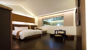 A modern bedroom with a large bed, a small sofa, a nightstand, and a window with blinds. - Yi Yuan Resort (Shoufeng)