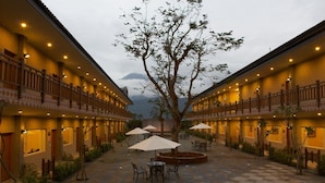 A courtyard with outdoor seating, a large tree, and a building with multiple balconies. - Yi Yuan Resort (Shoufeng)