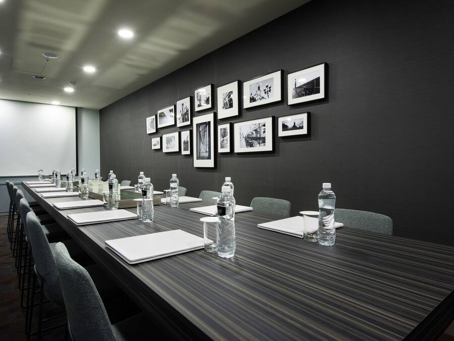 A conference room with a long table, chairs, water bottles, and framed pictures on the wall.