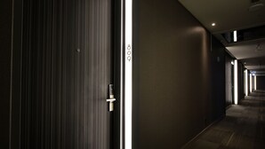 A hotel corridor with a modern design, featuring a combination of dark and light walls, a carpeted floor, and a door with a numeric keypad. - Hotel rêve Taichung (Taichung)