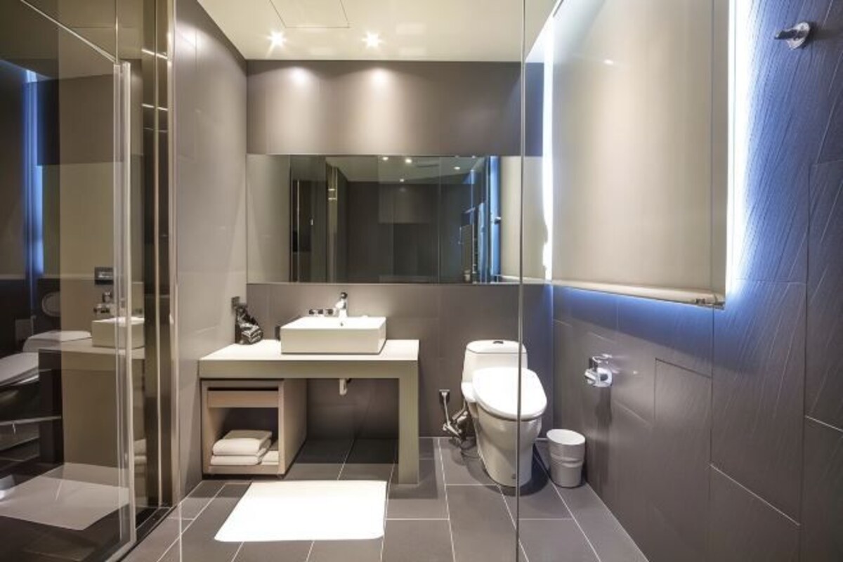 Un baño moderno con cabina de ducha de vidrio, un lavabo blanco y un inodoro.