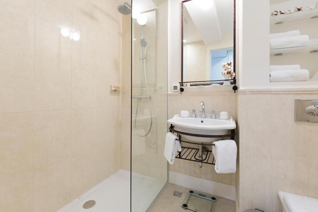 A modern bathroom with a glass-enclosed shower, a sink with a towel rack, and a mirror above the sink.