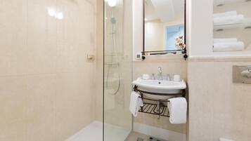 A modern bathroom with a glass-enclosed shower, a sink with a towel rack, and a mirror above the sink.
