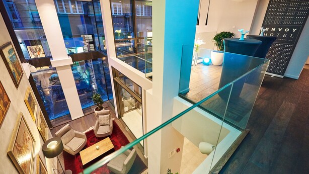 A modern hotel lobby with a glass railing, seating area, and a reception desk. - Envoy Hotel Belgrade (Belgrade)