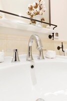 A modern bathroom with a white sink, chrome faucets, and a mirror above.