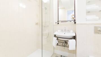 A modern bathroom with a glass shower enclosure, a sink with a towel rack, and a toilet.