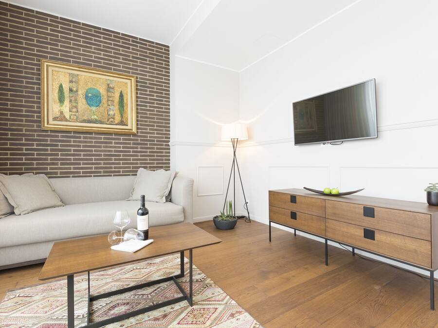 A modern living room with a sofa, coffee table, and a TV mounted on the wall.
