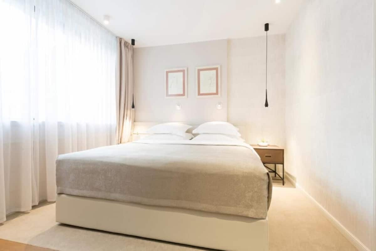 A modern bedroom with a large bed, a bedside table, and two framed pictures on the wall.