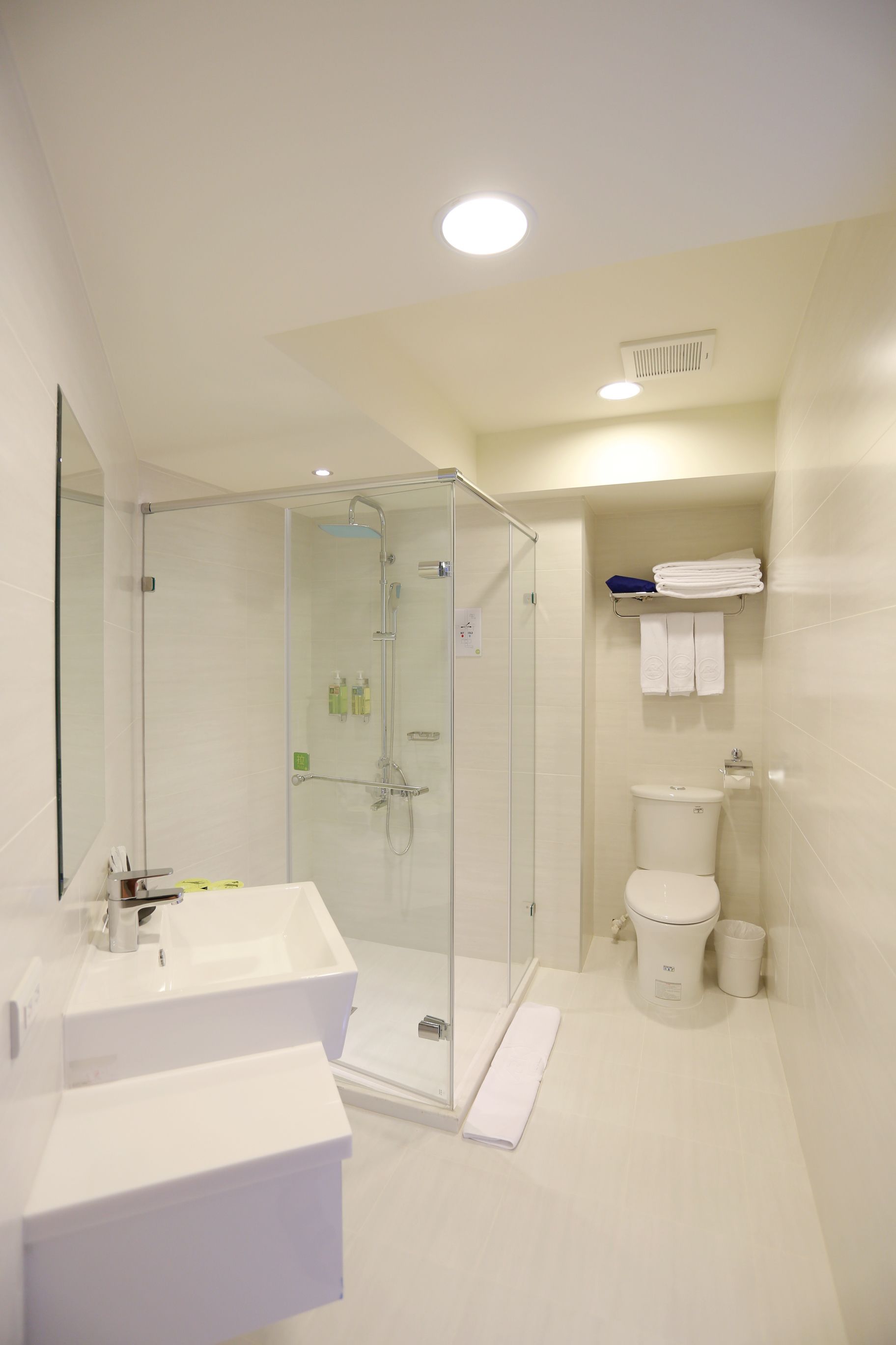 A modern bathroom with a glass-enclosed shower, a white sink, and a toilet.