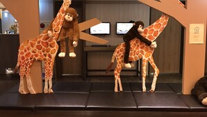 Ein Empfangsbereich mit einer Giraffe und einer Affügstatue, einem Empfangstresen und einem Bildschirm.