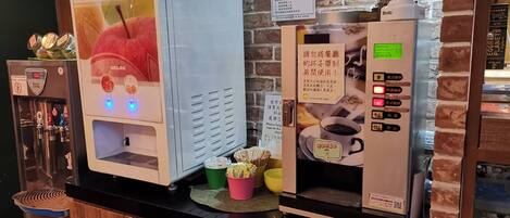 A coffee machine with a digital display and buttons, a water dispenser, and a coffee grinder on a counter with a brick wall background.