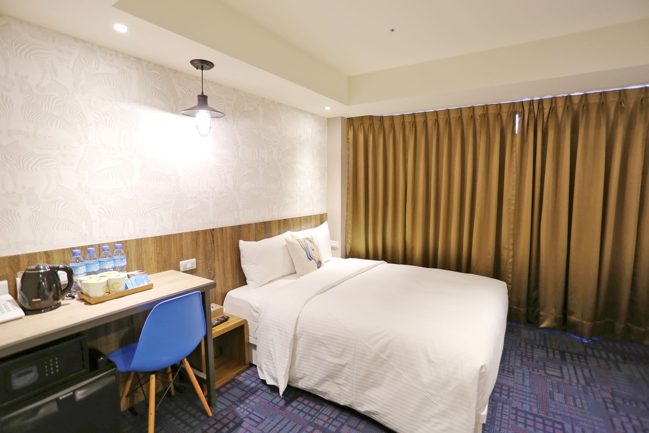 A hotel room with a bed, a desk with a chair, a microwave, and a coffee maker.