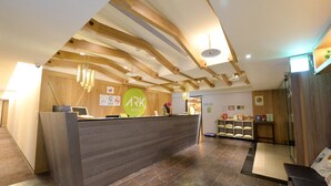 Ein Hotel-Rezeptionsbereich mit einem Holzbüro, einem Schild mit dem Hotelnamen und einer Sitzecke mit einer Bank.