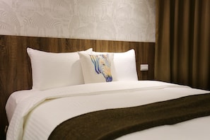 A neatly made bed with white linens and a decorative pillow featuring a zebra pattern.
