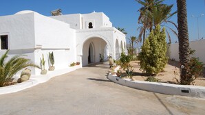 A white building with arches and a paved pathway. - Maison Leila (Mezraia)