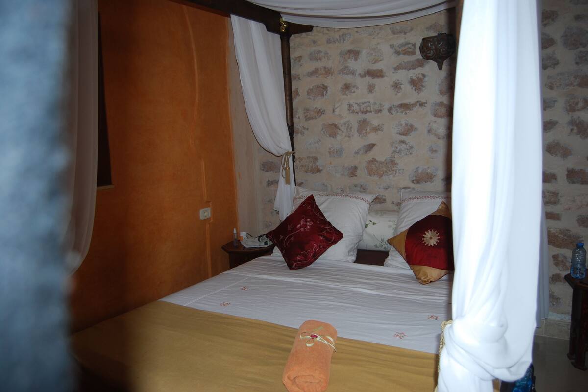 A hotel room with a bed, a nightstand, and a curtain.