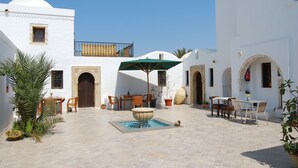 A courtyard with a fountain, outdoor seating, and potted plants. - Maison Leila (Mezraia)