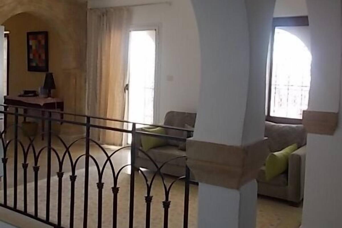 A spacious living area with a balcony, a dining area, and a view of the outside.