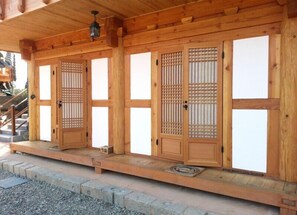 A traditional wooden building with multiple sliding doors, a wooden porch, and a lantern.