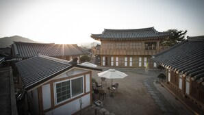 A traditional Korean courtyard with tiled roofs, wooden buildings, and a stone pathway. - Happy Village Syeobul Guesthouse (Gyeongju)