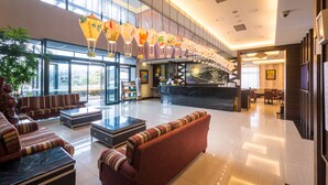A spacious lobby with a reception desk, seating area, and large windows.