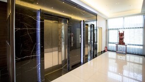 A modern elevator with a marble finish and a patterned wall.