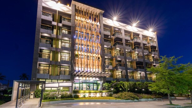 A multi-story hotel with a modern facade, balconies, and a well-lit entrance area.