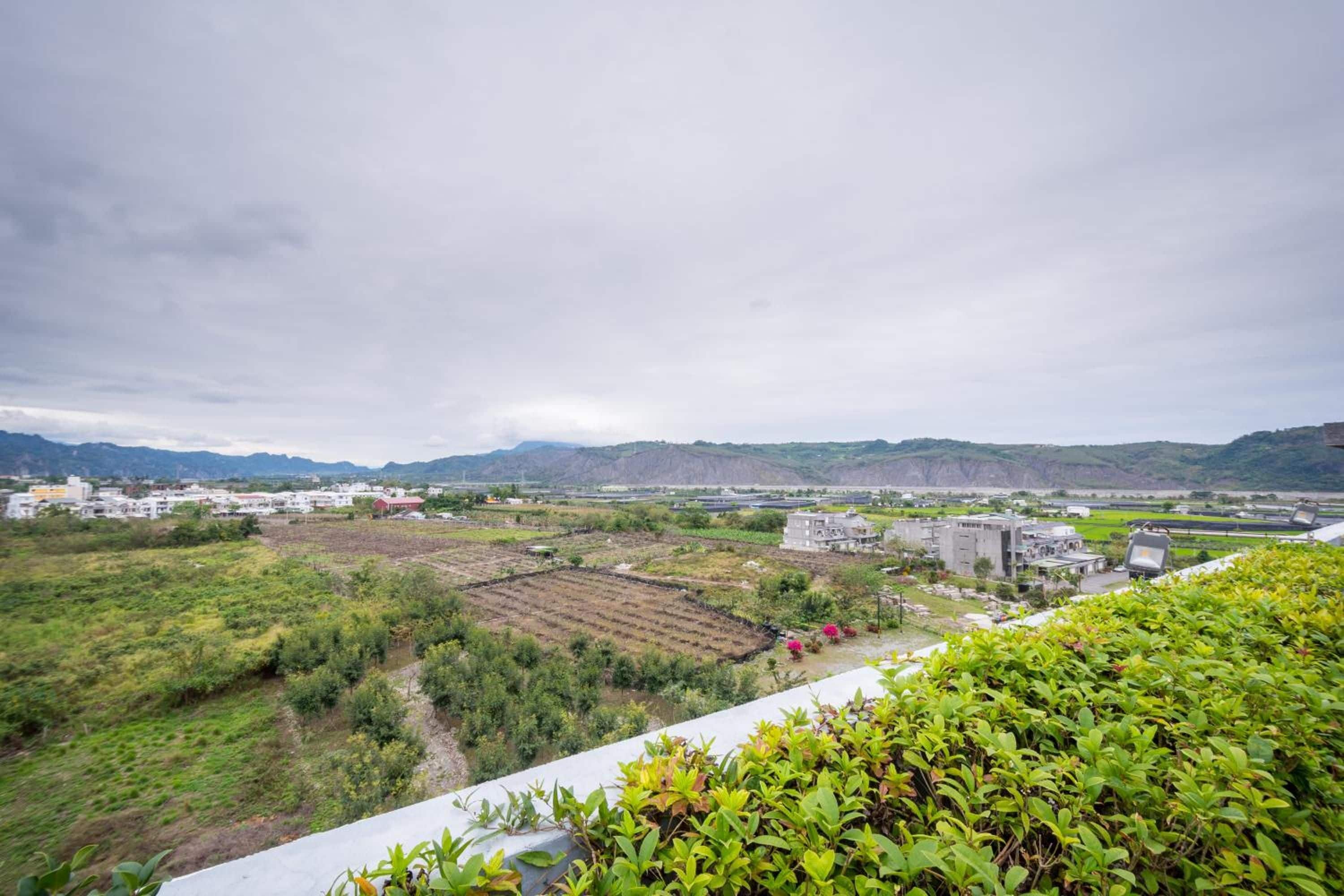 A landscape with buildings, fields, and distant mountains.