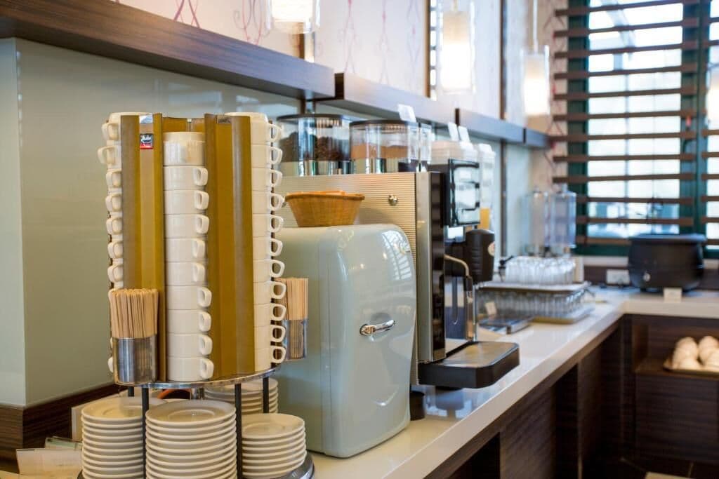 A coffee station with multiple coffee machines, a basket, and stacked plates.