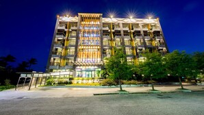 A multi-story hotel with a central atrium, balconies, and a well-lit entrance.