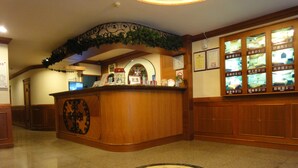 A reception area with a wooden counter, a clock, and framed certificates on the wall. - Taoyuan Hua Yue Hotel (Taoyuan City)