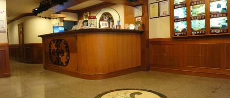 A reception area with a wooden counter, a clock, and framed certificates on the wall.